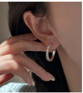 Macro view of S925 sterling silver hoop earring with industrial rivet gear texture