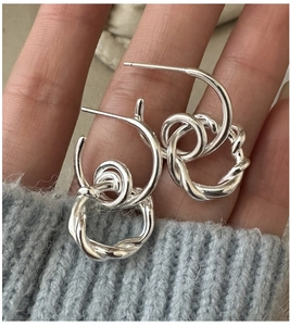 Detail of hand-held S925 sterling silver hoop earrings with twisted interlocking texture