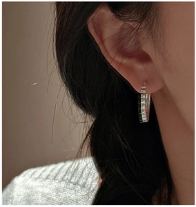 Close-up of minimalist S925 sterling silver geometric gear hoop earring on model ear