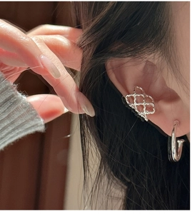 Macro shot of silver honeycomb ear cuff and minimalist hoop earring worn together