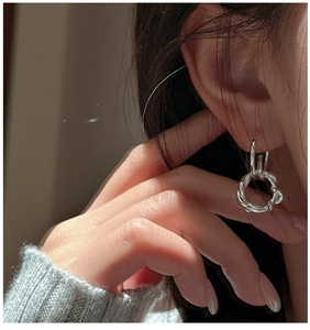 Close-up of S925 silver twisted hoop earrings worn for a stylish minimalist look