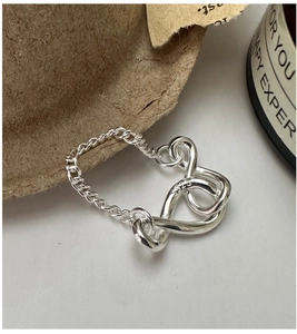Macro shot of S925 sterling silver infinity knot soft chain ring on a white surface