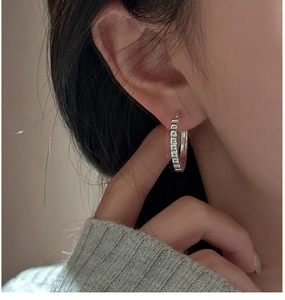 Close-up of S925 sterling silver hoop earring with geometric gear pattern on ear
