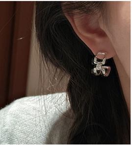 Macro detail of geometric silver earring with zircon stone worn by a model