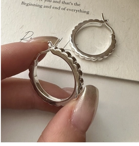 Macro shot of S925 sterling silver hoop earrings with wavy texture and engraved hallmark