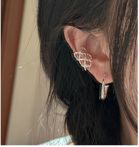 Detail of silver honeycomb ear cuff and nail design earring worn by a model