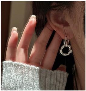 Close-up of model wearing silver S925 sterling silver twisted knot earrings