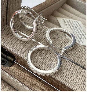Macro shot of S925 sterling silver scalloped hoop earring with hallmark in a jewelry box