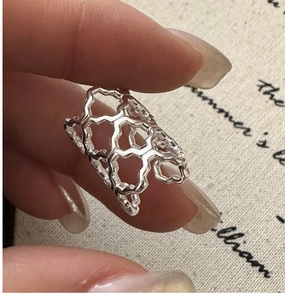 Detail of silver S925 geometric hollow ring with unique honeycomb pattern on hand