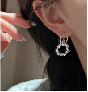 Detail view of wearing silver S925 interlocking rope textured hoop earrings for women
