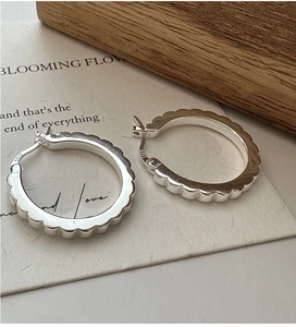 Macro shot of S925 sterling silver hoop earrings with a scalloped gear design and hallmark