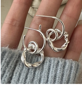 Detailed macro of S925 sterling silver twisted rope hoop earrings with polished texture