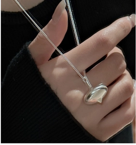 Macro shot of silver gyroscope pendant on a long chain against black knitwear