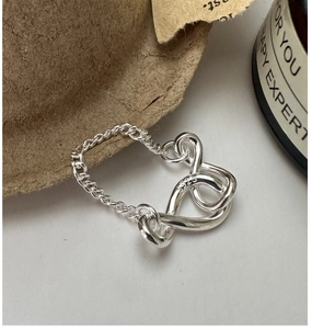 Macro shot of S925 sterling silver infinity knot ring with detailed Cuban chain texture