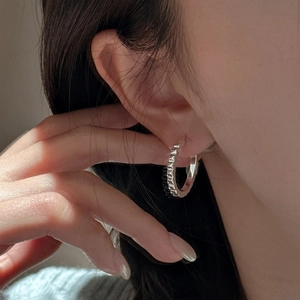 Minimalist S925 sterling silver hoop earring with geometric gear texture worn on ear