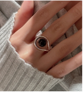 Detail of S925 sterling silver ring featuring a round black agate bead on a model's hand