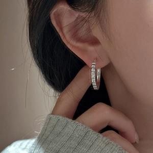 Elegant S925 sterling silver hoop earrings with textured gear design worn by a female model