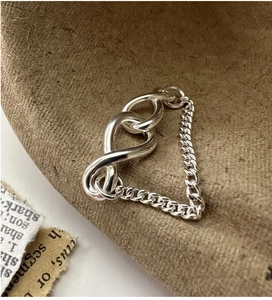 Close-up of S925 silver infinity heart knot chain ring on vintage paper background