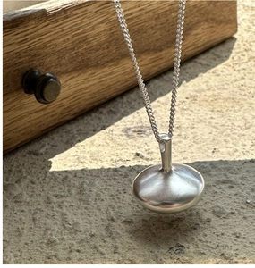 Close-up of polished S925 sterling silver spinning top pendant on beaded chain link