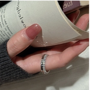 Primo piano dell'anello eternity in argento S925 con zirconi su sfondo di un libro