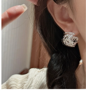 Close-up of S925 sterling silver hollow bird nest stud earrings on model's ear