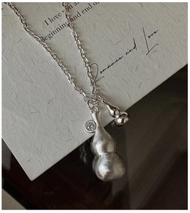 Detailed close-up of matte silver double gourd necklace with sparkling zircon on a link chain