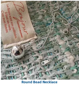 Macro shot of S925 sterling silver ball pendant necklace on green tweed fabric