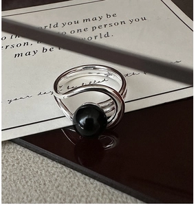 Close-up of S925 sterling silver ring with a smooth black onyx bead on a reflective surface