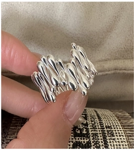 Vue macro d'une bague en métal argenté liquide avec un design de goutte sur la main