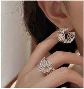 Macro shot of S925 sterling silver hollow earrings and ring set in liquid metal style