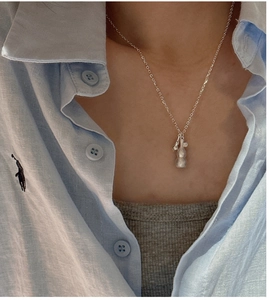 Detail of 925 sterling silver gourd necklace on model with minimalist blue shirt background