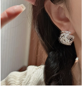 Close-up of S925 sterling silver stud earring with irregular wire nest design on ear