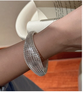 Close-up of wide hollow silver mesh bracelet with sleek 3D geometric design on wrist