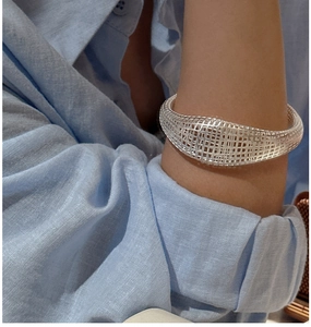 Detail of the woven hollow mesh design on a polished silver S925 sterling silver bangle