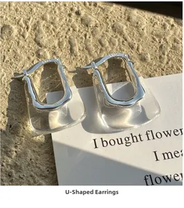 Gros plan de boucles d'oreilles en argent en U avec résine sur pierre texturée