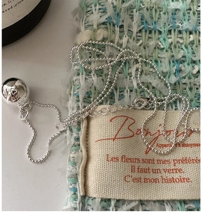 Close-up of polished S925 silver bead chain necklace with engraved heart pendant on tweed