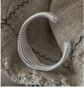 Detailed macro view of S925 sterling silver hollow mesh bracelet on textured linen