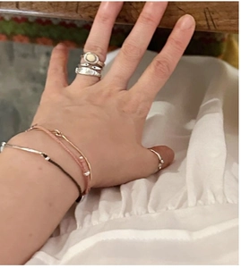 Détail de bagues empilables en argent S925 et bracelets tressés portés par un modèle