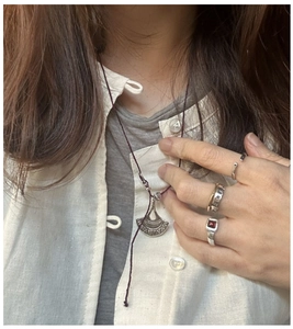 Dettaglio di anelli e collana in argento vintage su modella con accenti di pietra rossa