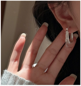 Gros plan d'une boucle d'oreille argentée en U portée par un mannequin sous le soleil