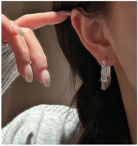 Gros plan de boucles d'oreilles créoles irrégulières en argent avec texture de lave