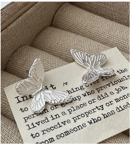 Macro detail of S925 sterling silver butterfly earrings with intricate relief texture