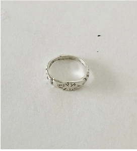 Détail macro d'une bague en argent S925 avec motif d'étoile gravé et finition vintage