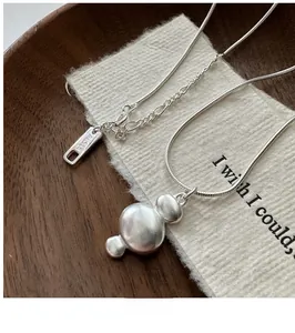 Detail of S925 sterling silver stamp on irregular matte pendant with snake bone chain