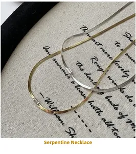 Detail of minimalist gold and silver flat snake chains with zircon inlay on linen fabric