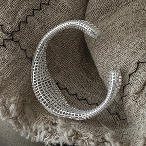 Minimalist S925 sterling silver hollow grid cuff bracelet on rustic linen fabric