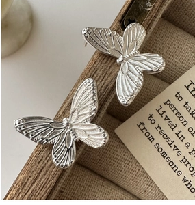 Macro shot of S925 sterling silver butterfly earrings with brushed metal texture details