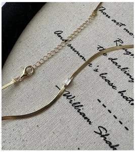 Macro shot of gold snake chain necklace featuring a rectangular zircon stone and lobster clasp