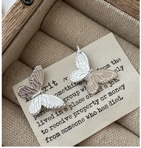 Macro shot of S925 sterling silver butterfly earrings with detailed engraved texture