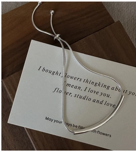 Macro shot of silver minimalist snake chain bracelet with adjustable slider and curved tube